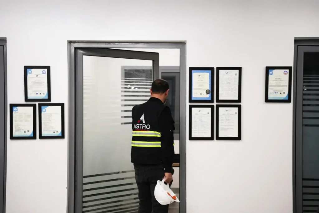 Astro Cables employee walking past certifications in the office.