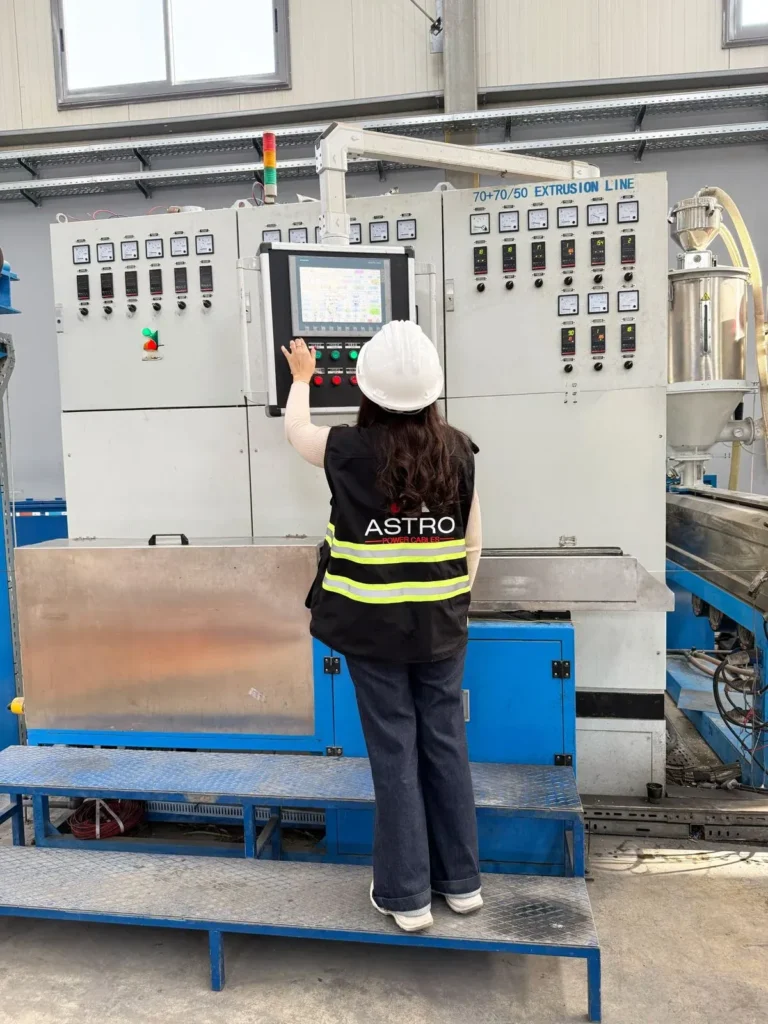 Worker operating Astro Cables' extrusion machine in factory.
